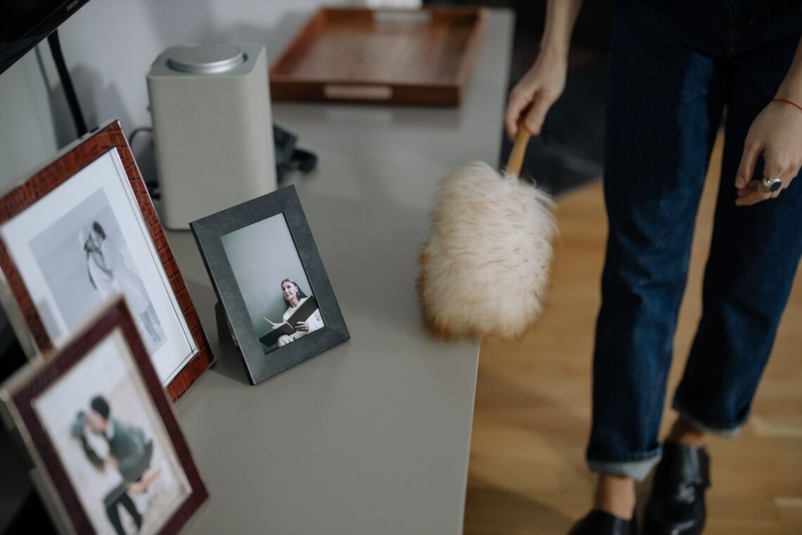 Astma a alergie: Skutečný důvod, proč vaše děti doma kašlou 7 A woman using a feather duster to clean picture frames on shelves indoors